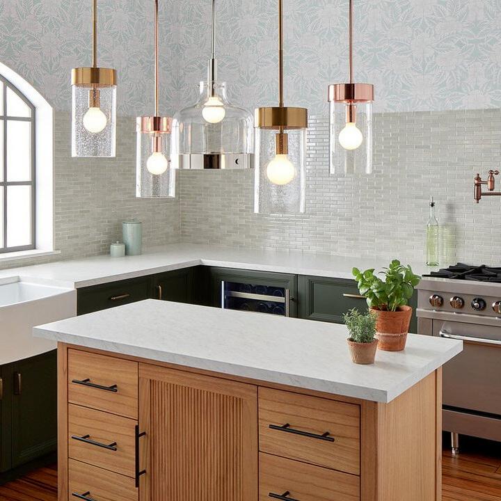 Pendant lights in Polished Nickel, Bright Copper, Brushed Gold hang over a kitchen island