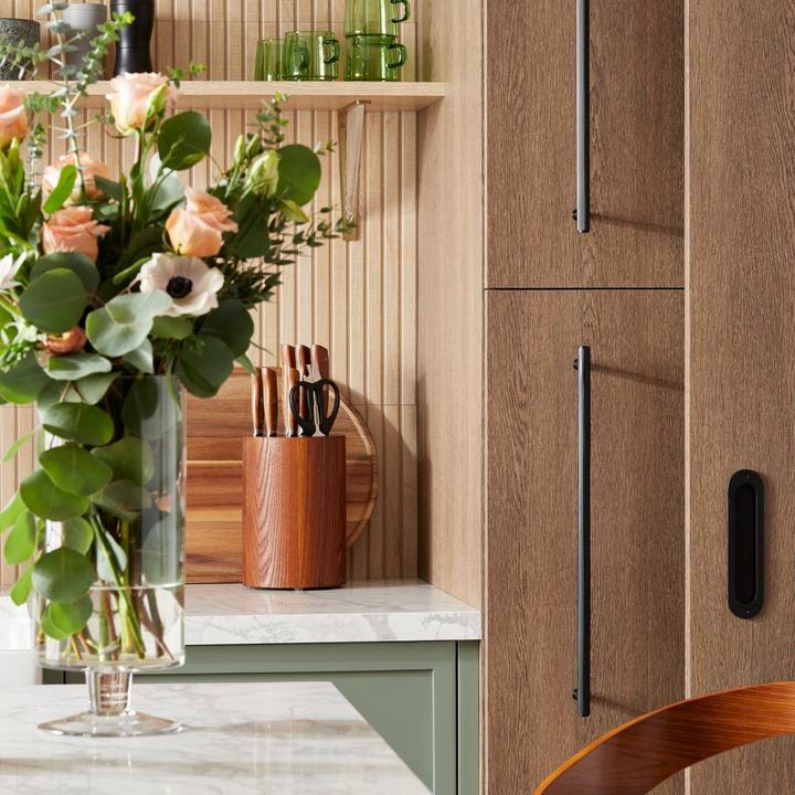 Hidden kitchen with the Brixlee Reeded Brass Appliance Pull & Elongated Oval Recessed Brass Pocket Door Pull in Matte Black