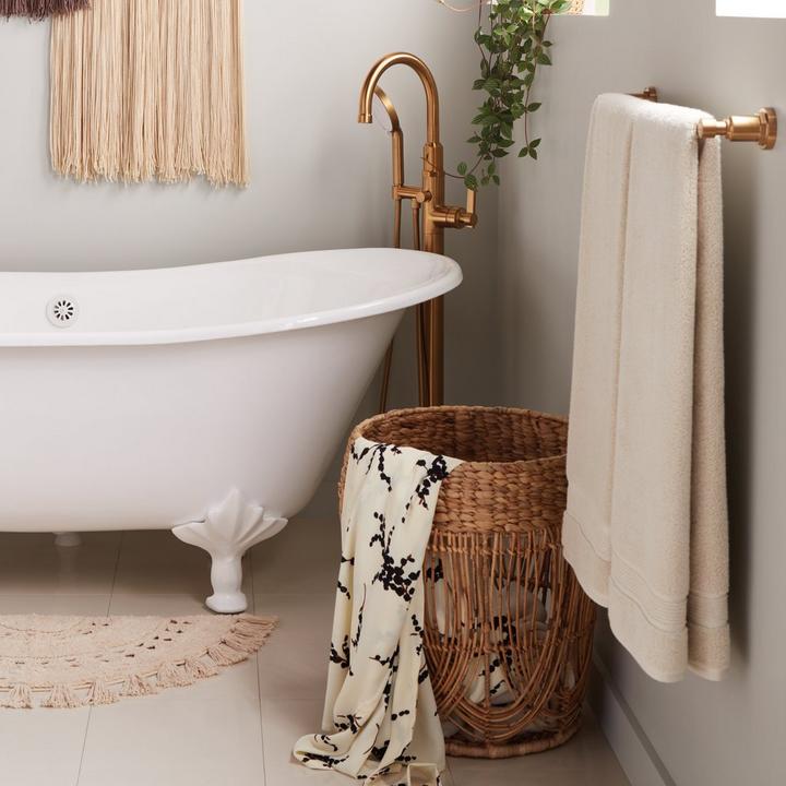 A woven basket next to the Waller Caston Iron Clawfoot Tub & Greyfield Tub Faucet in Brushed Gold for home decor tips